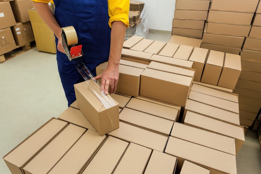 Person taping cardboard boxes in warehouse.
