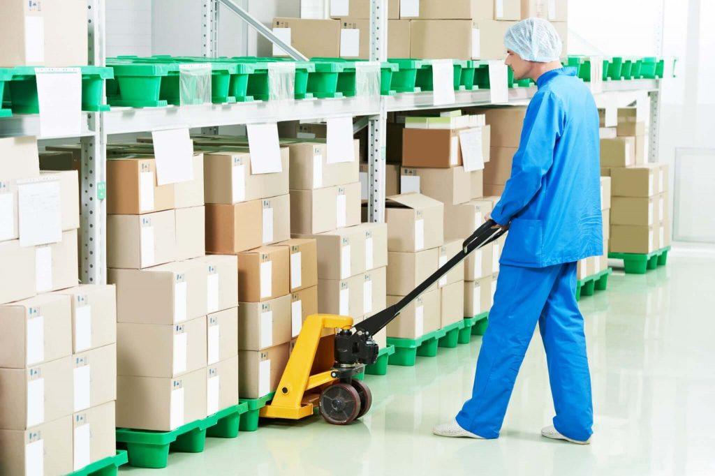 Worker moving boxes in sterile warehouse.