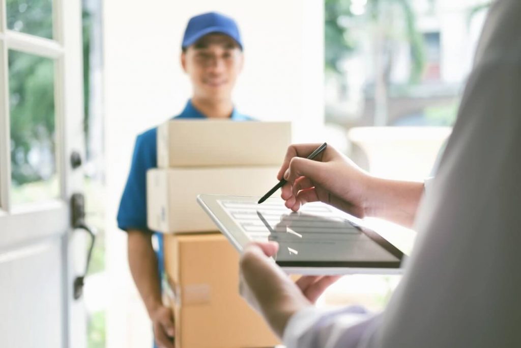 Delivery person handing over packages at doorway.