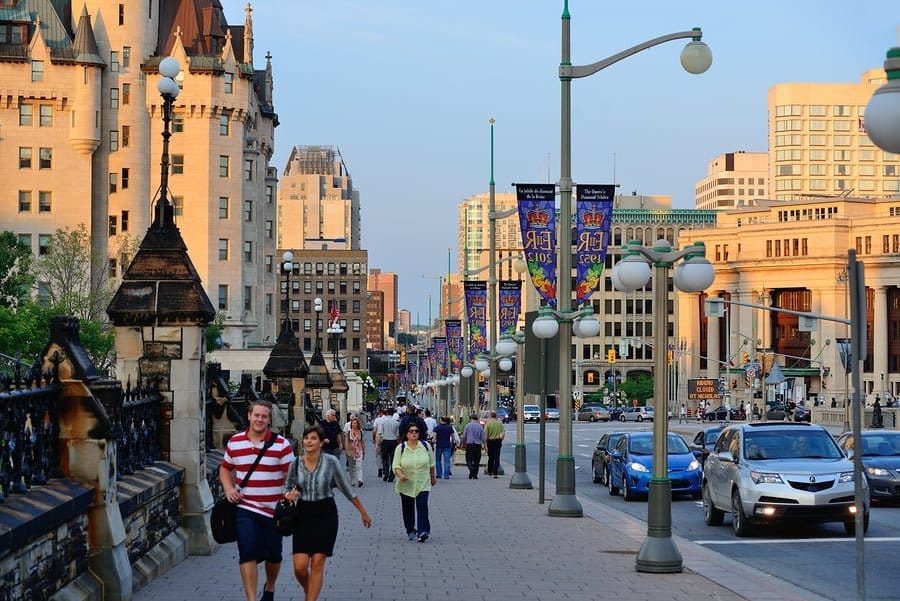People walking on busy city street, cars passing by.