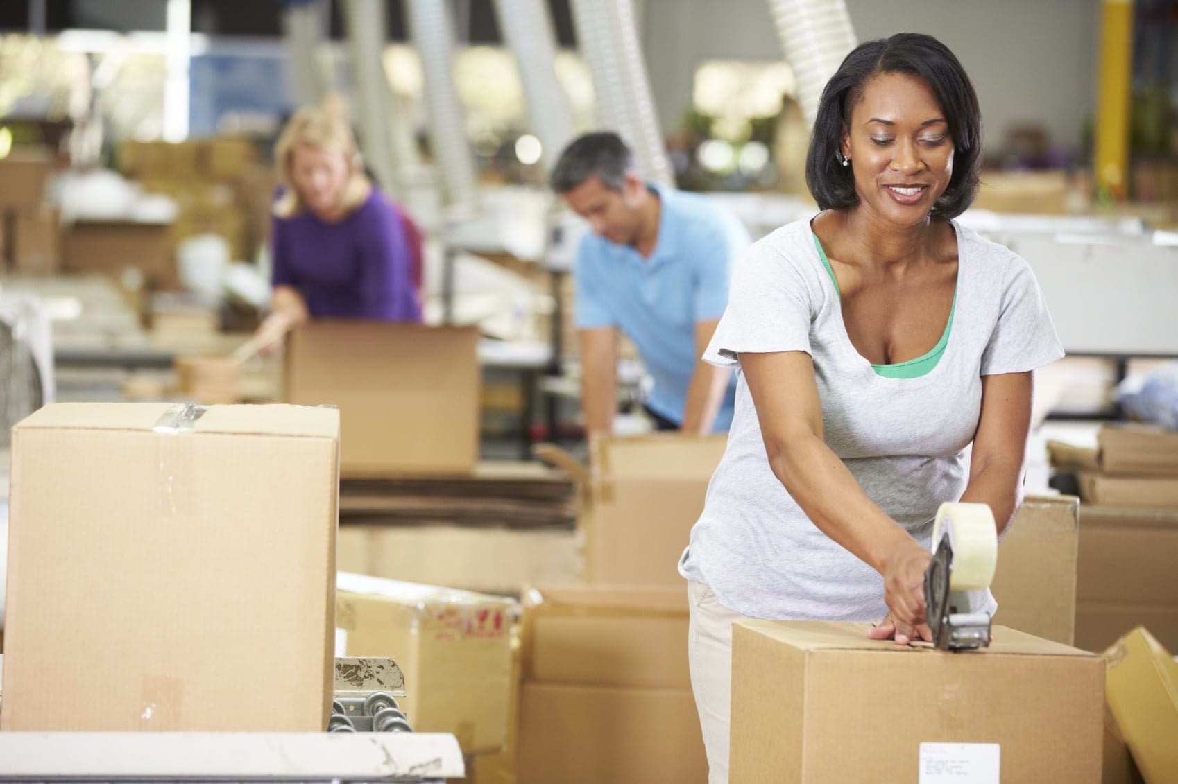 Workers packaging and kitting boxes in a factory setting